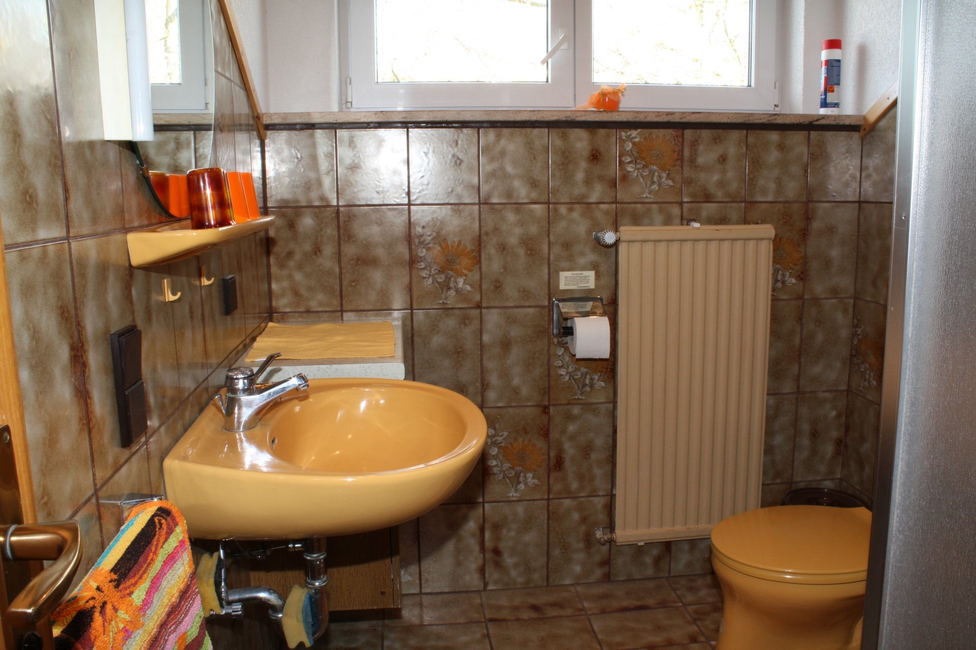 Badezimmer mit Waschbecken, Toilette und Fenster.