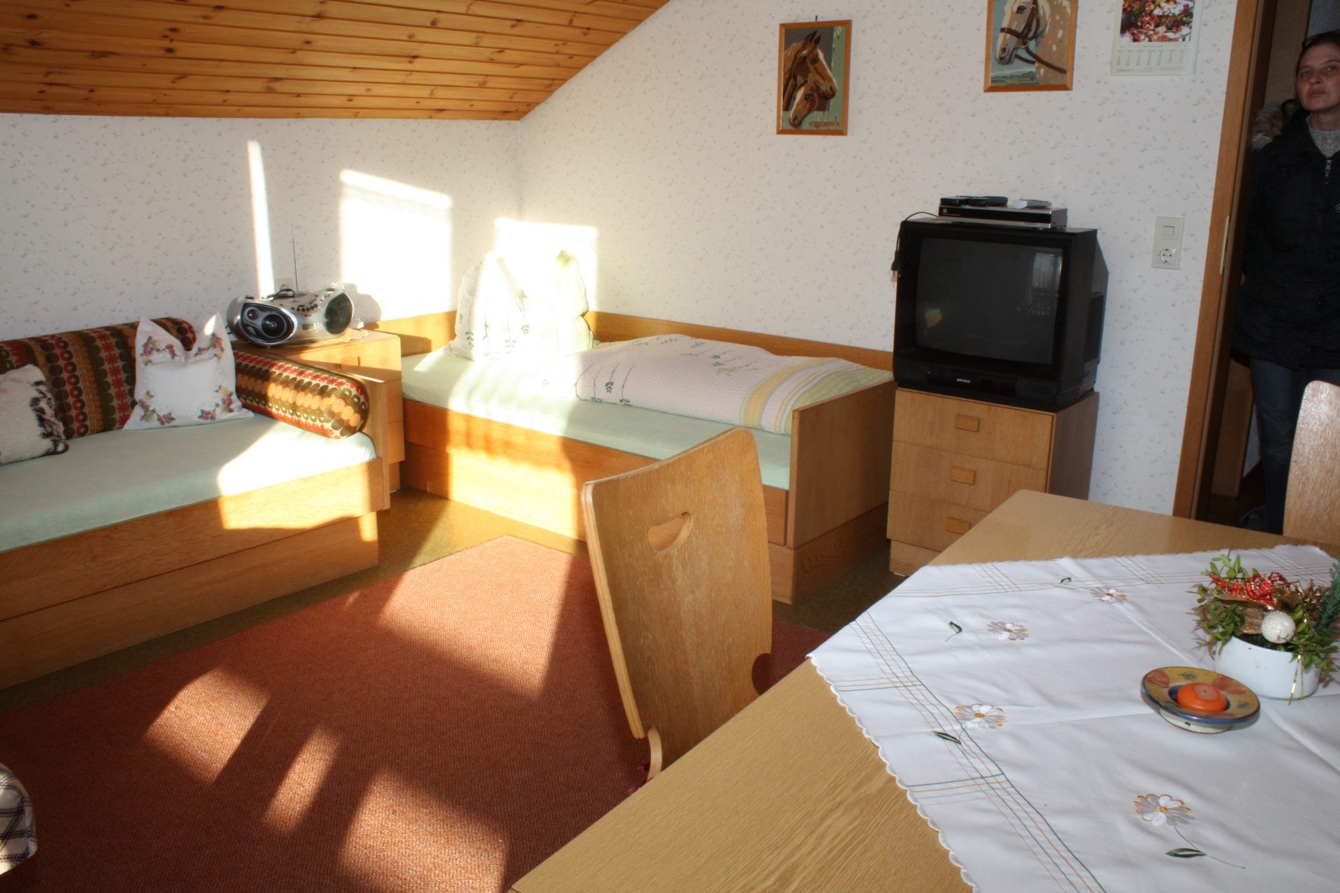Wohnbereich mit zwei Schlafcouches, Fernseher und Esstisch unter der Dachschräge.