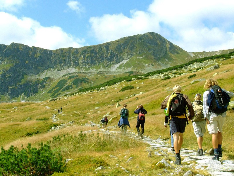 Eine Wandergruppe folgt einem steinigen Pfad durch ein Hochgebirgstal.